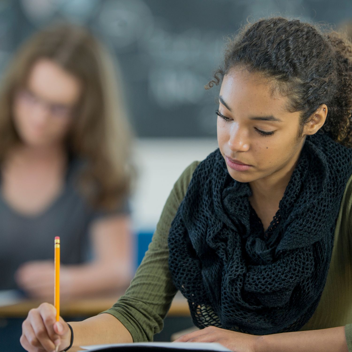 Image of a young person writing with a pencil at an exam table