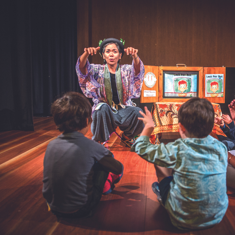 Storyteller Anna Manuel performs an interactive kamishibai storytelling session as children sit on the floor and join in.