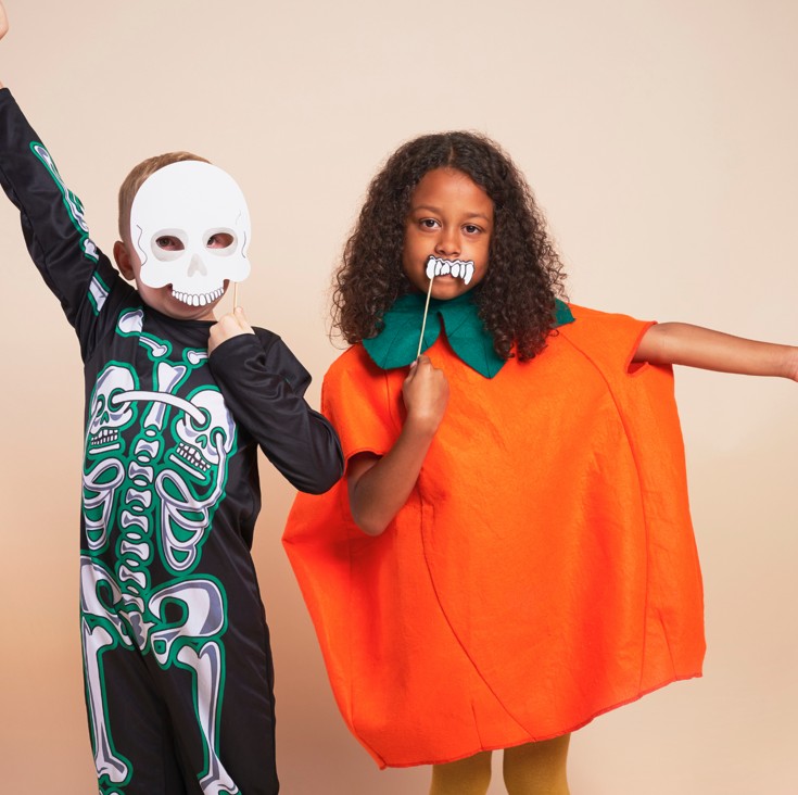two children dressed for Halloween as a pumpkin and a skeleton