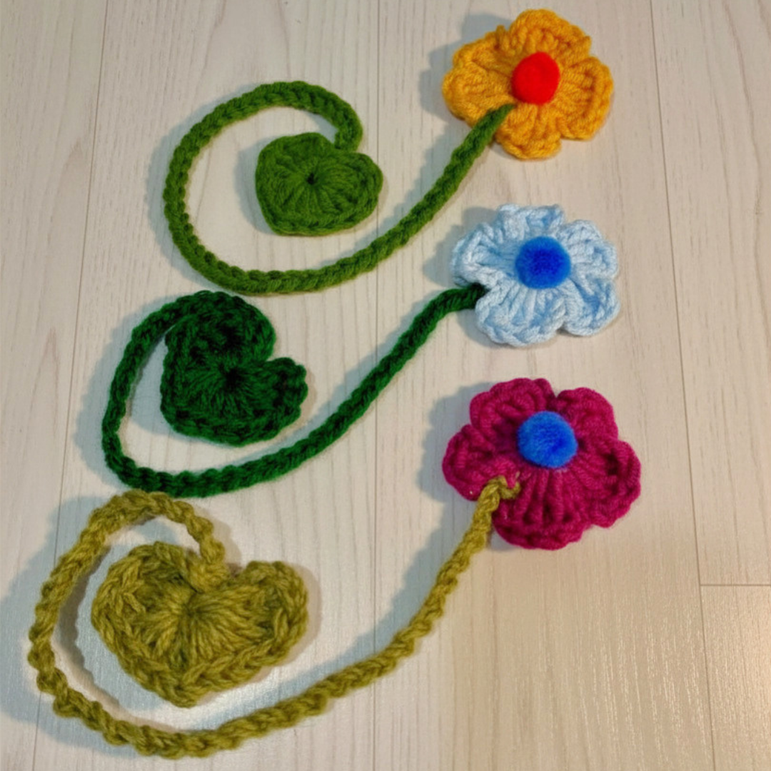 Three crochet flowers with stems that are curling at the end