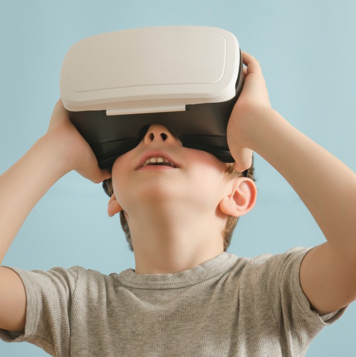 Image of a young person aged around 9 or 10 with a VR headset on, looking upwards.