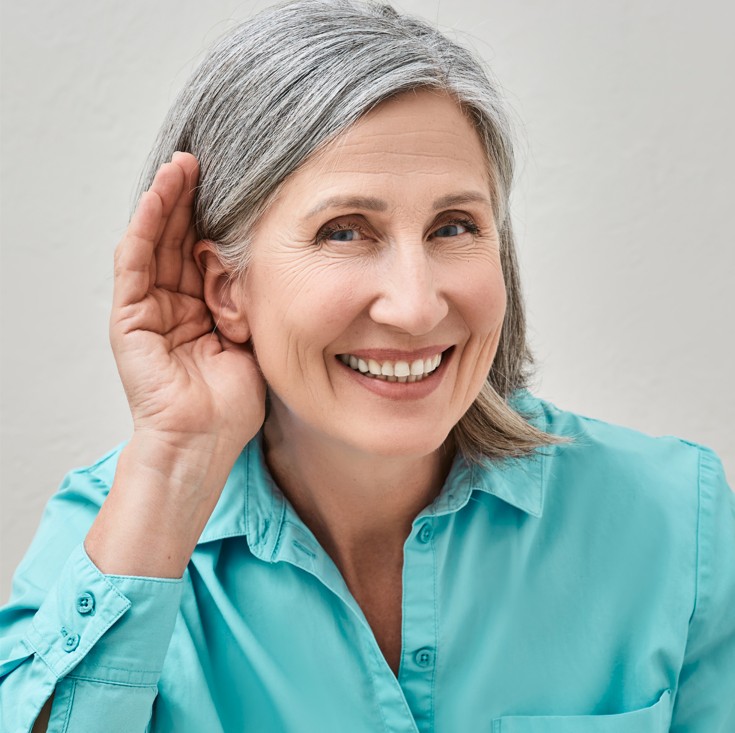 Image of a lady holding her hand up to her ear in a listening gesture