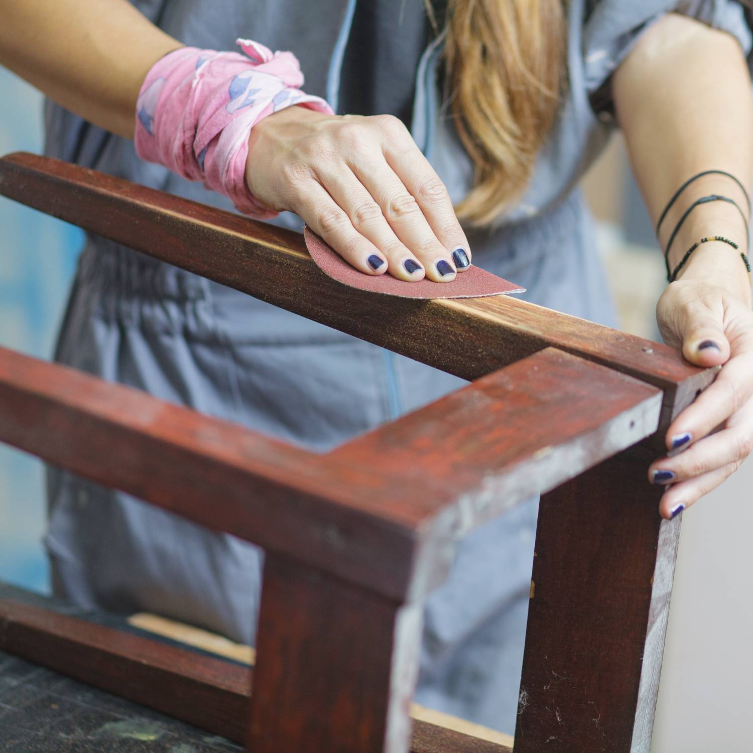 Image of a person sanding back a chair.
