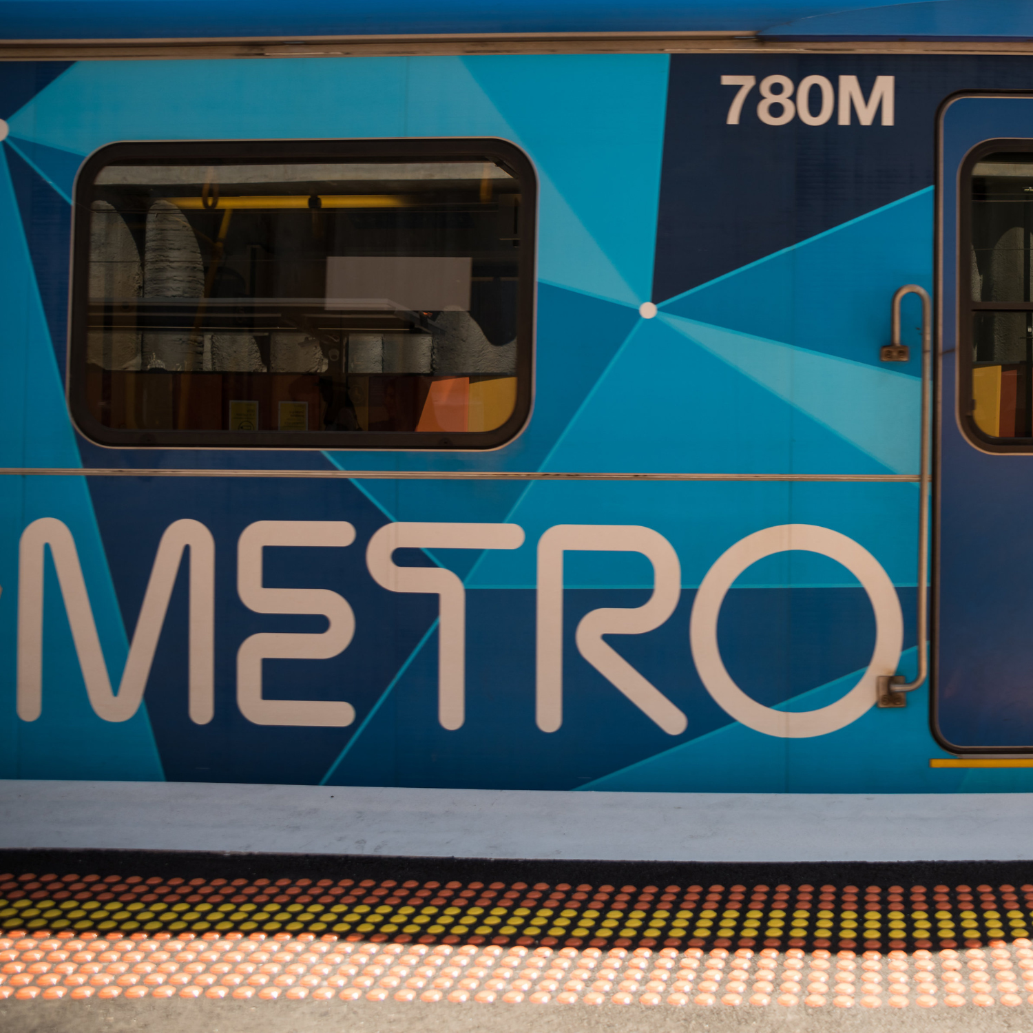 A close up photo of the side of a train stationed at a platform. Metro is written on the side of the train.