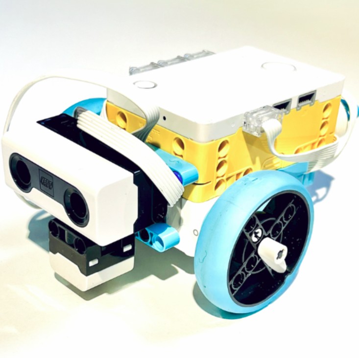 A small LEGO robot with two large blue wheels and a front sensor that looks like eyes.