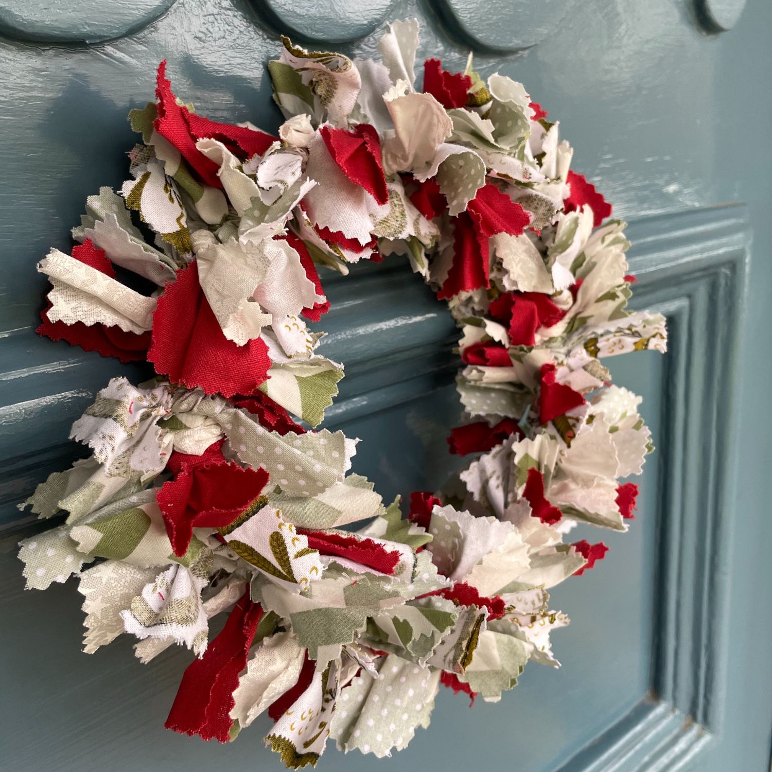 A festive wreath hanging on a door made out of recycled fabrics